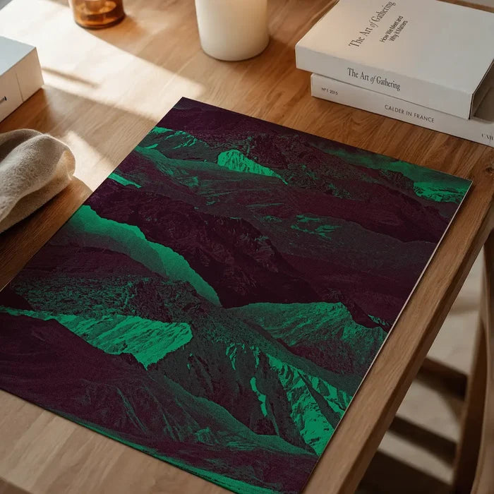 Abstract green and dark purple mountain print on thick art paper, displayed on a wooden table.