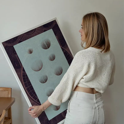Woman holding a dark astrology chart print with vintage space diagrams and planets on light blue.
