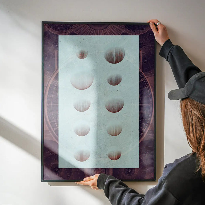 Hands hanging a dark framed Astrology Chart Dark Print with vintage space diagram style.