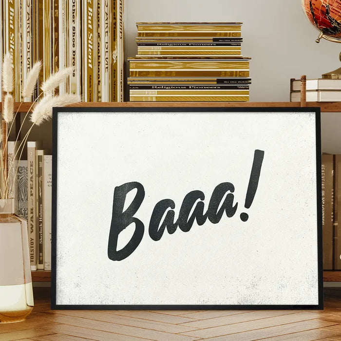 Minimalist "Baaa!" animal sound print with black brush script on a textured off-white background in a black frame.