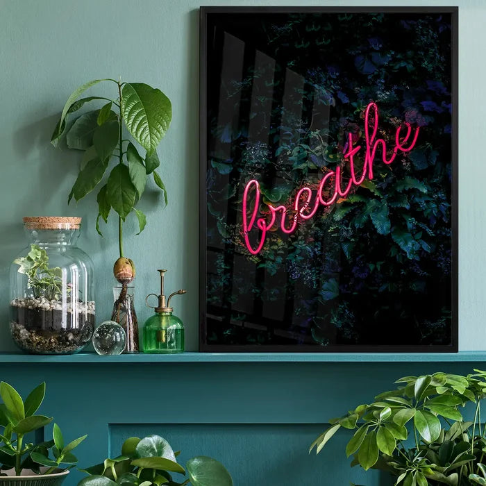 Breathe" neon sign print with vibrant pink script on a dark botanical background, framed in black.