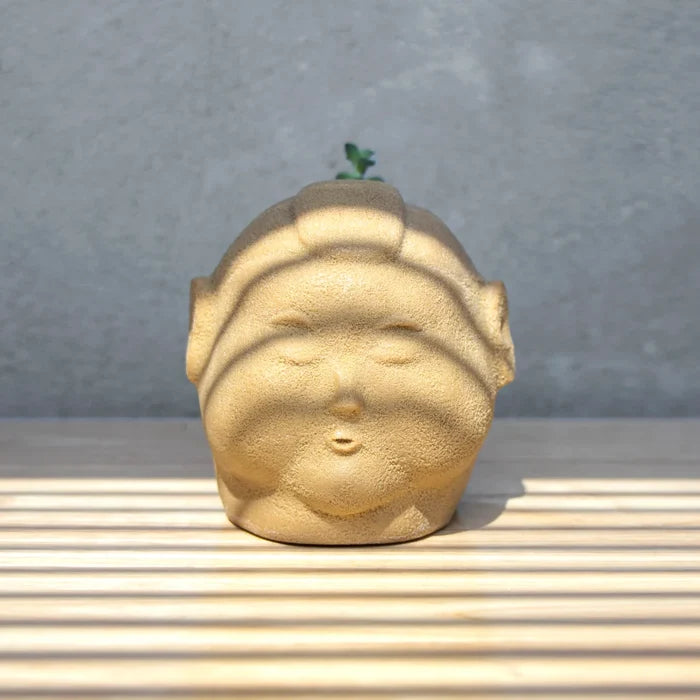 A small child statue with a plant growing on top, part of the CHUNK MOHAWK PLANTER by Jim Dreams collection.