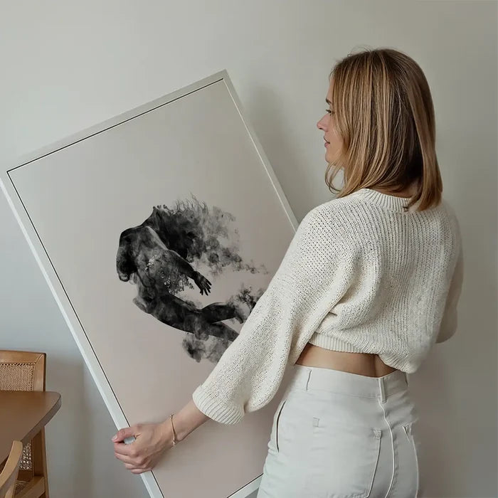 Abstract female form dancing in clouds on pastel pink art print, held by a woman.