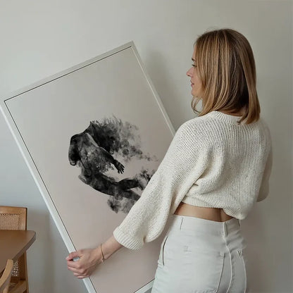Abstract female form dancing in clouds on pastel pink art print, held by a woman.