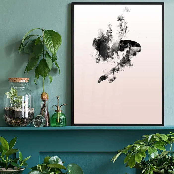 Abstract female form dancing in clouds on a pastel pink art print, framed in black, on a green shelf.