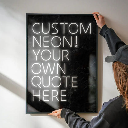 Person holding a framed custom white neon-style quote print on a black marble background.