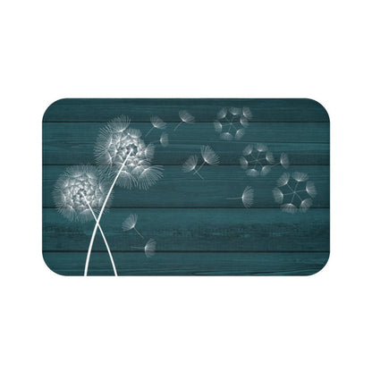 A rectangular memory foam mat with a printed design of white dandelions on a dark teal background, featuring an anti-slip backing.