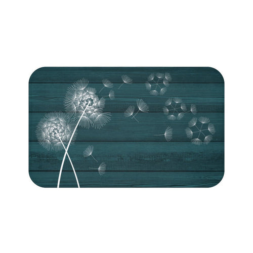 A rectangular memory foam mat with a printed design of white dandelions on a dark teal background, featuring an anti-slip backing.