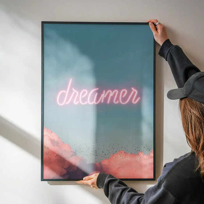 Framed Dreamer Clouds Neon Print with pink neon text and clouds on a blue sky background.