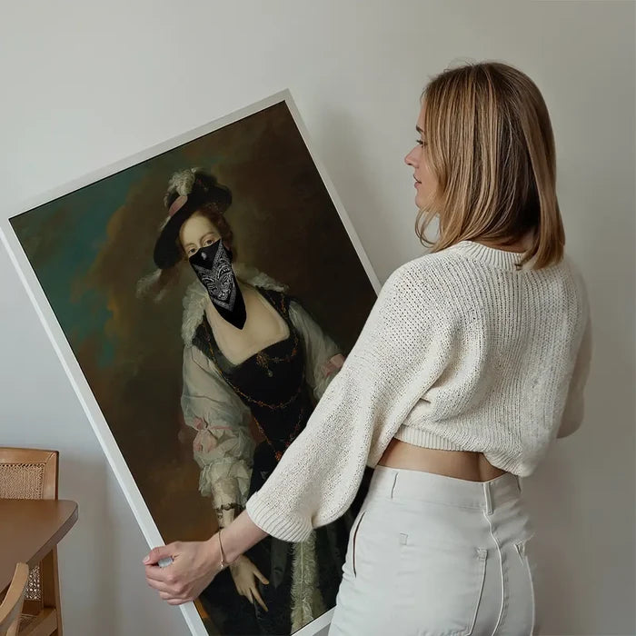 Woman holding a framed "Gang Portrait Female Print" showing a vintage painting with a black bandana mask.
