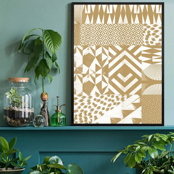 Gold geometric segments print in a black frame, displayed on a teal shelf with plants.