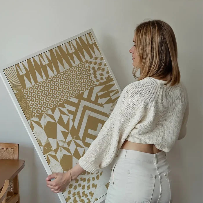 Woman holding a framed "Geometric Segments Gold Print" with abstract patterns on archival art paper.