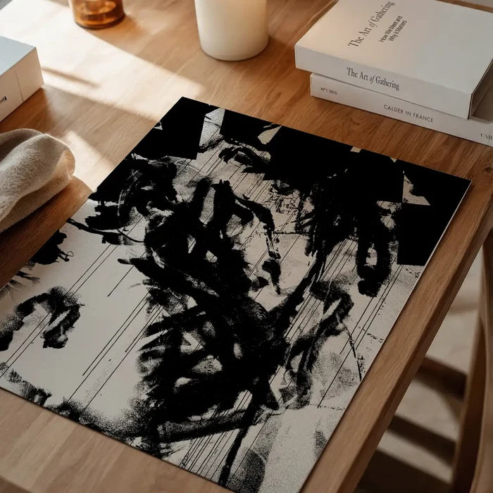 Abstract black and white graffiti art print on thick paper, displayed on a wooden table.