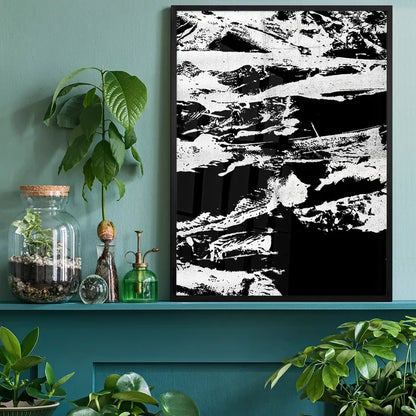 Black and white abstract graffiti print in a black frame, on a green wall above a shelf with plants.
