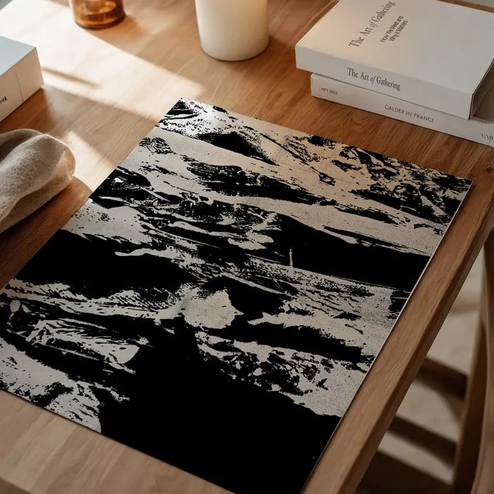 Black and white abstract graffiti print on thick art paper, displayed on a wooden table.