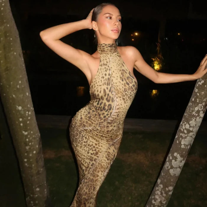 Woman in a leopard print outfit posing outdoors at night.