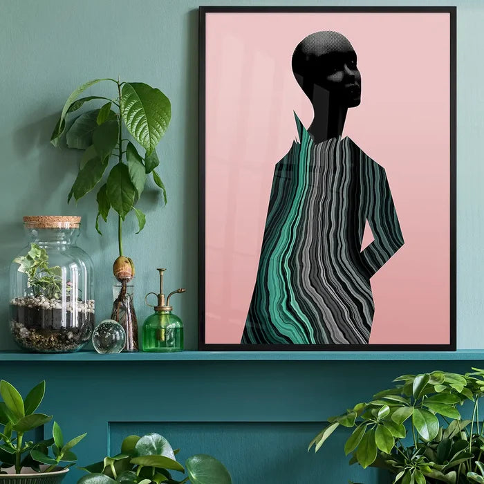Abstract female form art print with black marble textures on a pink background, framed on a green shelf.