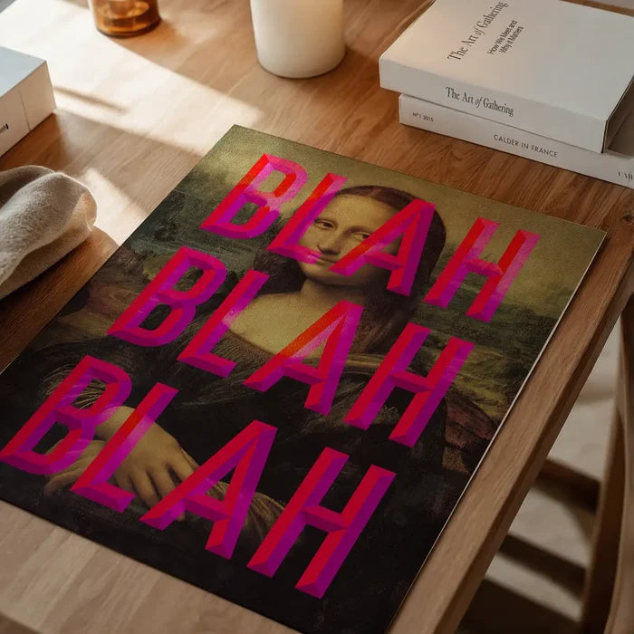 Contemporary Mona Lisa print with "BLAH BLAH BLAH" in bold pink typography, displayed on a wooden table.