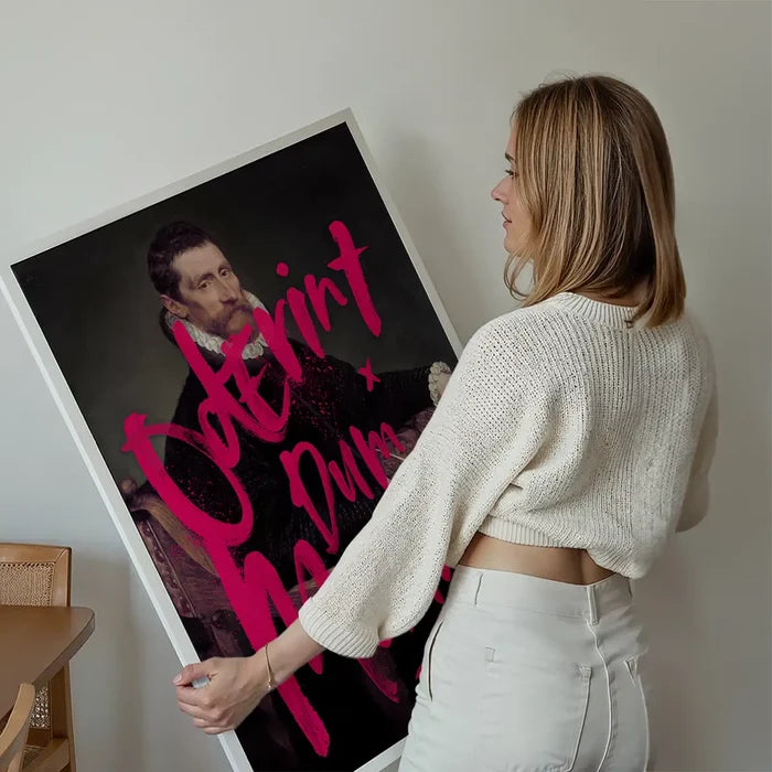 Woman holding a large "Oderint Dum Metuant" graffiti print on thick art paper, featuring a classic portrait with neon pink text.