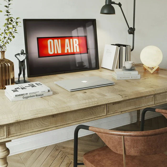 Retro "ON AIR" lightbox print on a wooden desk with a laptop, books, and a moon lamp.