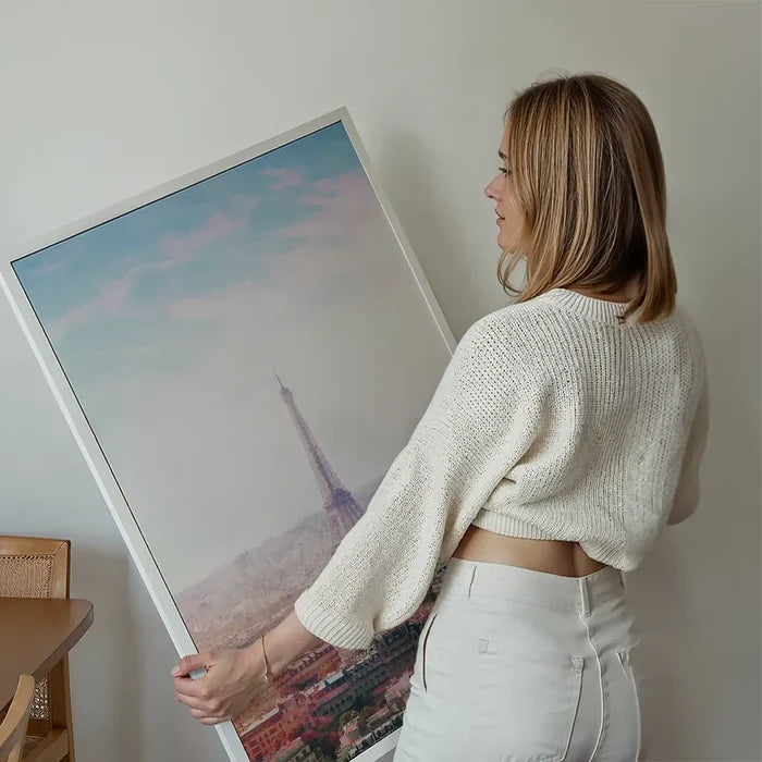 Woman holding a framed Paris Eiffel Tower city photography print with an abstract pink hue.