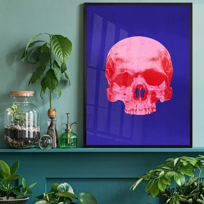 Pop Art Warhol style blue and pink skull print framed on a teal wall with plants.