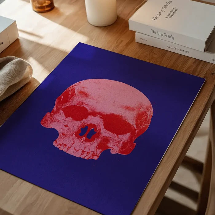 Warhol-style blue and pink skull print on thick art paper, displayed on a wooden table.