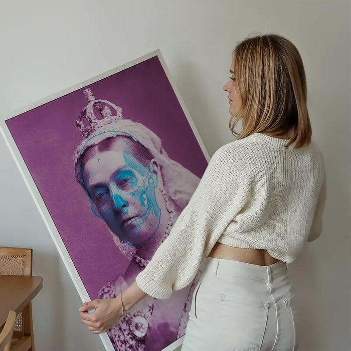 Woman holding a framed Queen Victoria skull colour print with purple background and blue skull overlay.