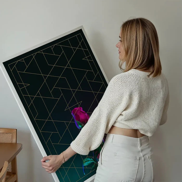 Woman holding a striking rose print with gold geometric lines on dark archival art paper.