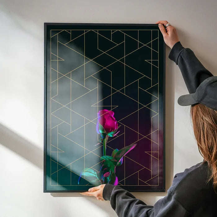 Rose print with gold geometric lines on black, held by hands, framed in black.