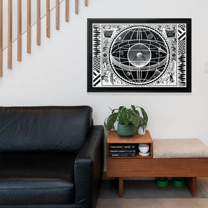 Black framed Sceno Systematis Astrology print with vintage graphic style, hanging above a black leather sofa.