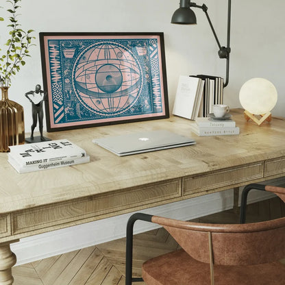 Framed Sceno Systematis Astrology Pink Print on a wooden desk with a laptop, books, and moon lamp.