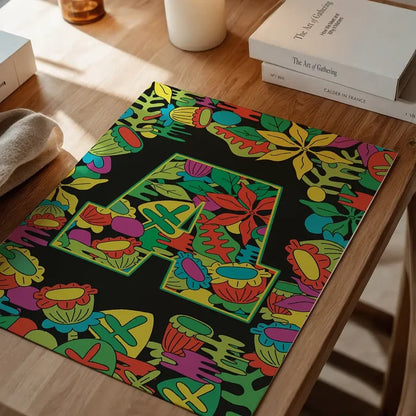 Black print with a large green leafy letter "A" surrounded by colorful flowers and leaves.