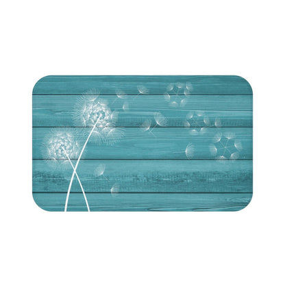 A rectangular memory foam mat with a teal background and a white dandelion design.