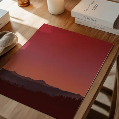 Duotone sunset art print on thick paper, featuring a red and orange sky over dark mountains and trees.