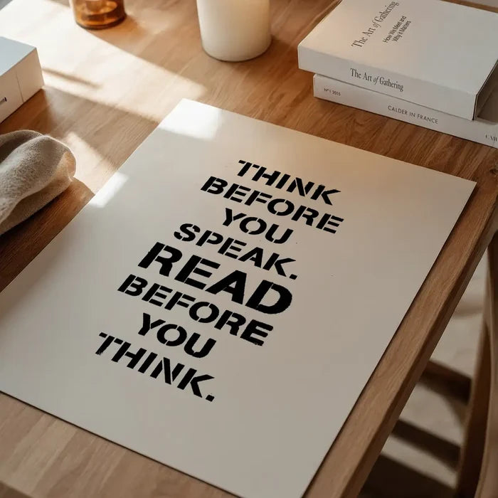 White typographic print on wood table: "Think Before You Speak. Read Before You Think.