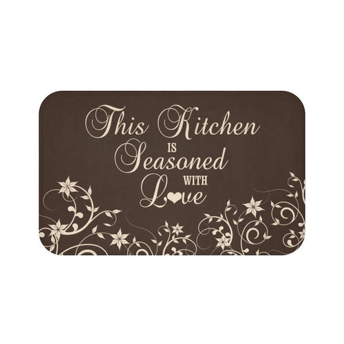 Floor mat with brown background and tan vine pattern across bottom of the mat. The phrase "This Kitchen is Seasoned with Love" is written in tan cursive script in the center.