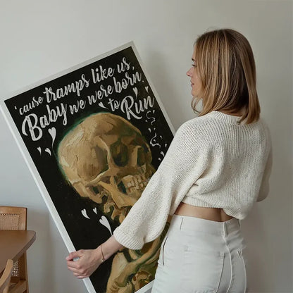 Woman holding a "Tramps Like Us" lyrics print featuring a classic skull painting on black art paper.
