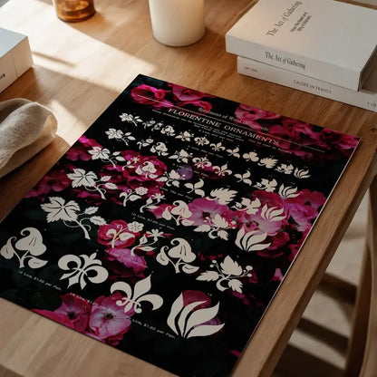 Black typographic floral print with white Florentine ornaments and vibrant pink roses on a wooden table.
